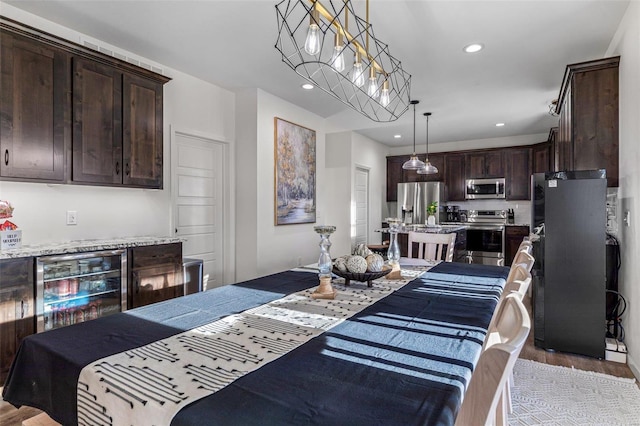 kitchen with dark brown cabinets, dark hardwood / wood-style flooring, pendant lighting, stainless steel appliances, and light stone countertops