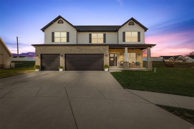 view of front facade with a garage, covered porch, and a lawn