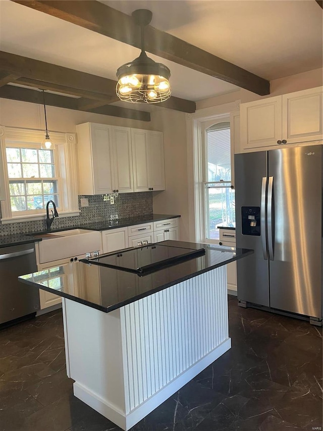 kitchen featuring stainless steel appliances, a healthy amount of sunlight, white cabinets, and beam ceiling