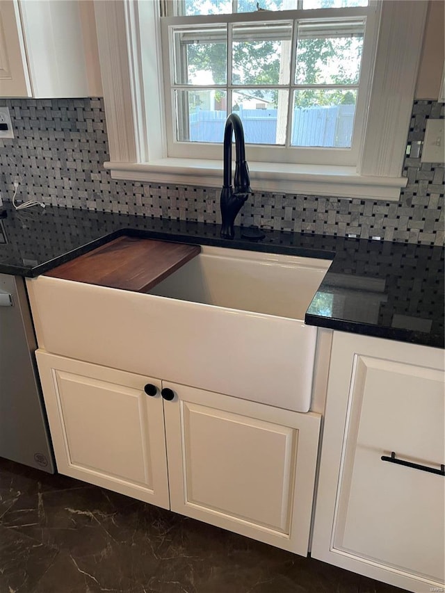 room details featuring dishwasher, sink, white cabinets, and backsplash