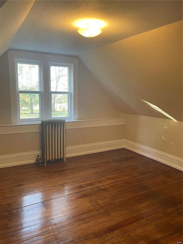 bonus room with vaulted ceiling, dark hardwood / wood-style floors, and radiator heating unit