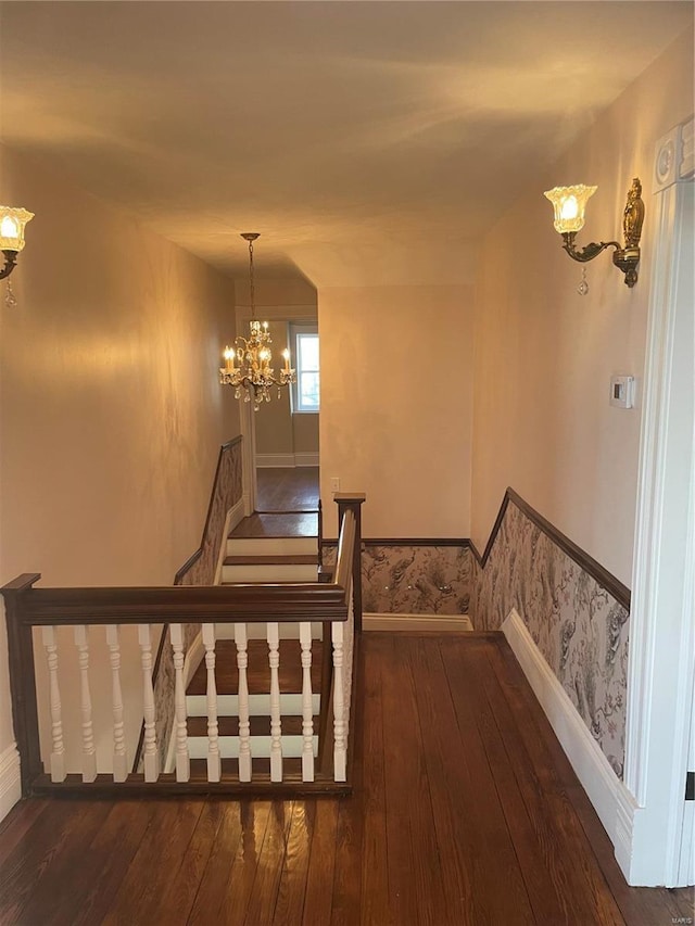 stairs featuring hardwood / wood-style flooring and a notable chandelier