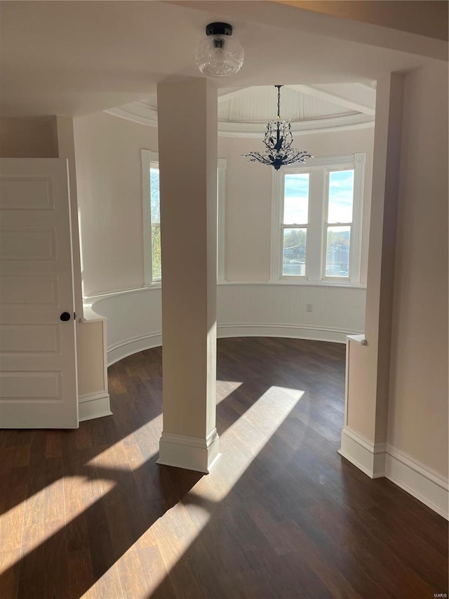 empty room with an inviting chandelier and dark hardwood / wood-style flooring