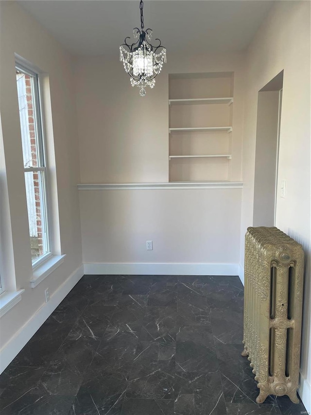 unfurnished dining area featuring an inviting chandelier, radiator, built in shelves, and a healthy amount of sunlight