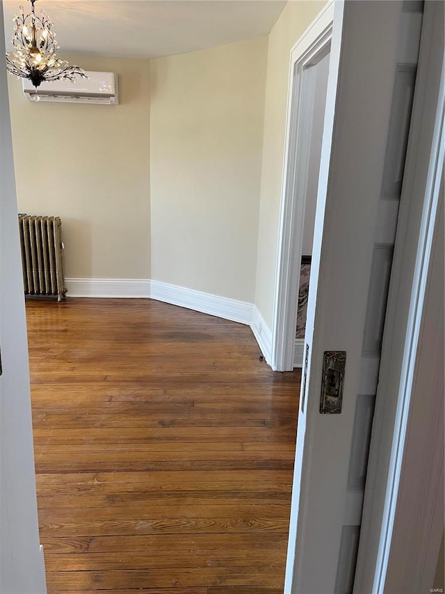 interior space featuring radiator, hardwood / wood-style flooring, a notable chandelier, and an AC wall unit