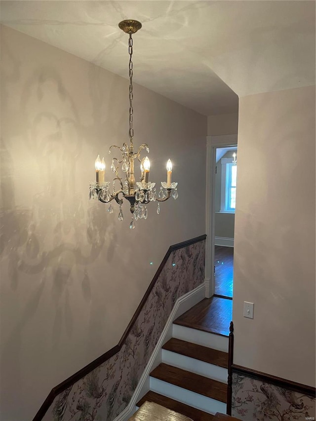 staircase with a notable chandelier