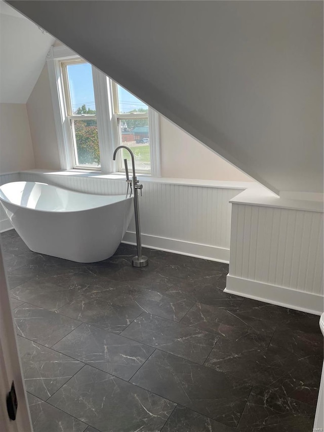 bathroom featuring vaulted ceiling and a washtub