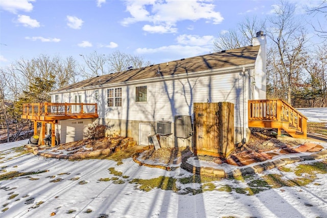 snow covered rear of property featuring a deck