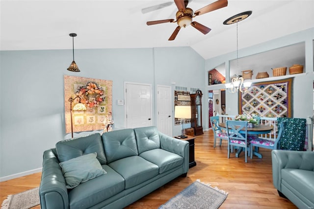 living room featuring vaulted ceiling, ceiling fan with notable chandelier, and light hardwood / wood-style floors