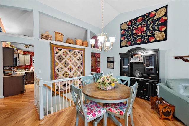 dining space with light hardwood / wood-style flooring, vaulted ceiling, and an inviting chandelier