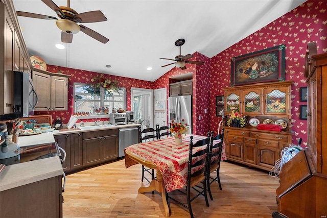 kitchen featuring sink, ceiling fan, stainless steel appliances, light hardwood / wood-style floors, and vaulted ceiling