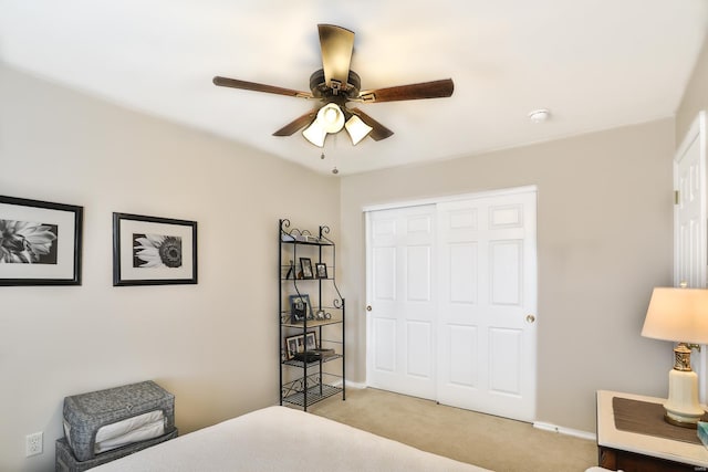 bedroom featuring light colored carpet, ceiling fan, and a closet