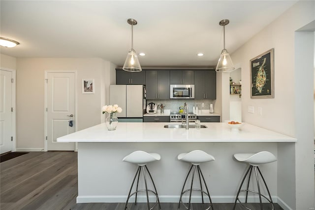 kitchen with sink, a breakfast bar area, appliances with stainless steel finishes, hanging light fixtures, and backsplash