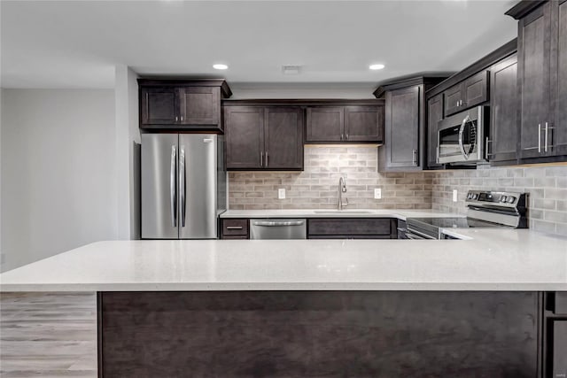 kitchen featuring dark brown cabinetry, appliances with stainless steel finishes, sink, and backsplash