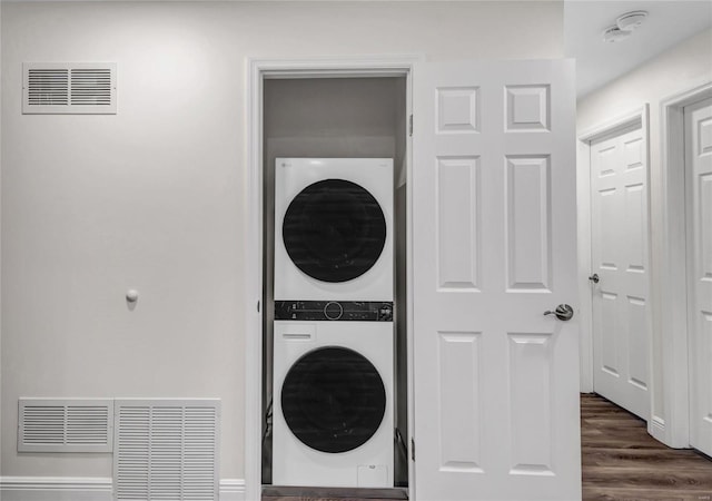 washroom with dark wood-type flooring and stacked washer and dryer