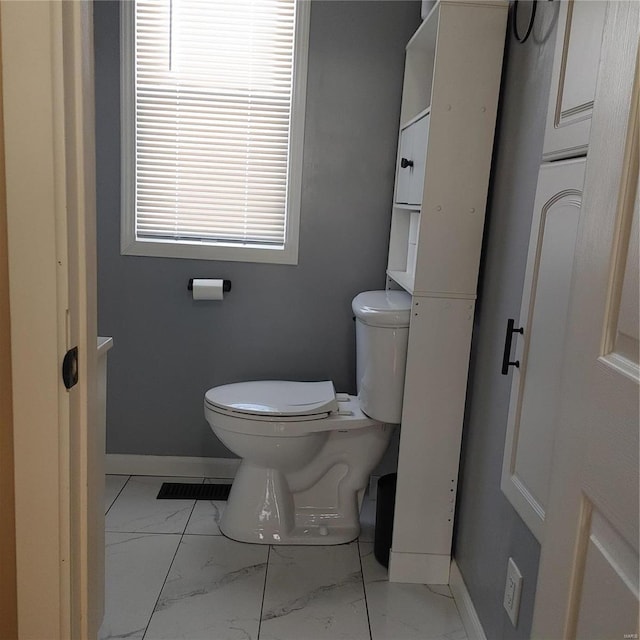 bathroom featuring toilet, marble finish floor, and baseboards