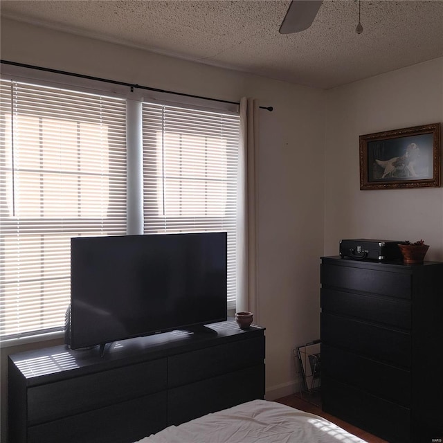 bedroom featuring a ceiling fan, a textured ceiling, and baseboards