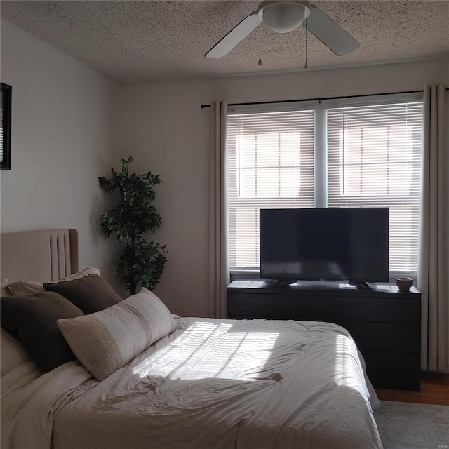 bedroom featuring ceiling fan, wood-type flooring, and a textured ceiling