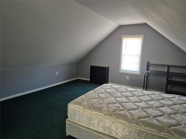 bedroom featuring lofted ceiling, dark carpet, and baseboards