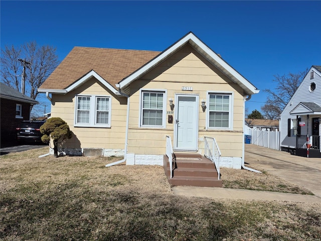 bungalow featuring a front yard, fence, and roof with shingles