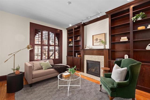 living area with rail lighting, light wood-type flooring, and built in shelves