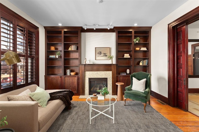 living area featuring built in shelves, track lighting, and hardwood / wood-style flooring