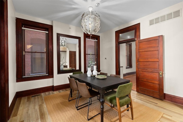 dining area with light hardwood / wood-style floors and a chandelier