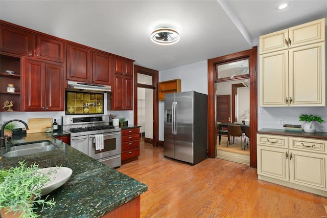 kitchen with sink, light hardwood / wood-style flooring, cream cabinetry, stainless steel appliances, and backsplash