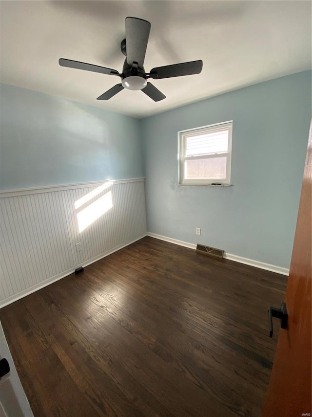 empty room with ceiling fan and dark hardwood / wood-style flooring