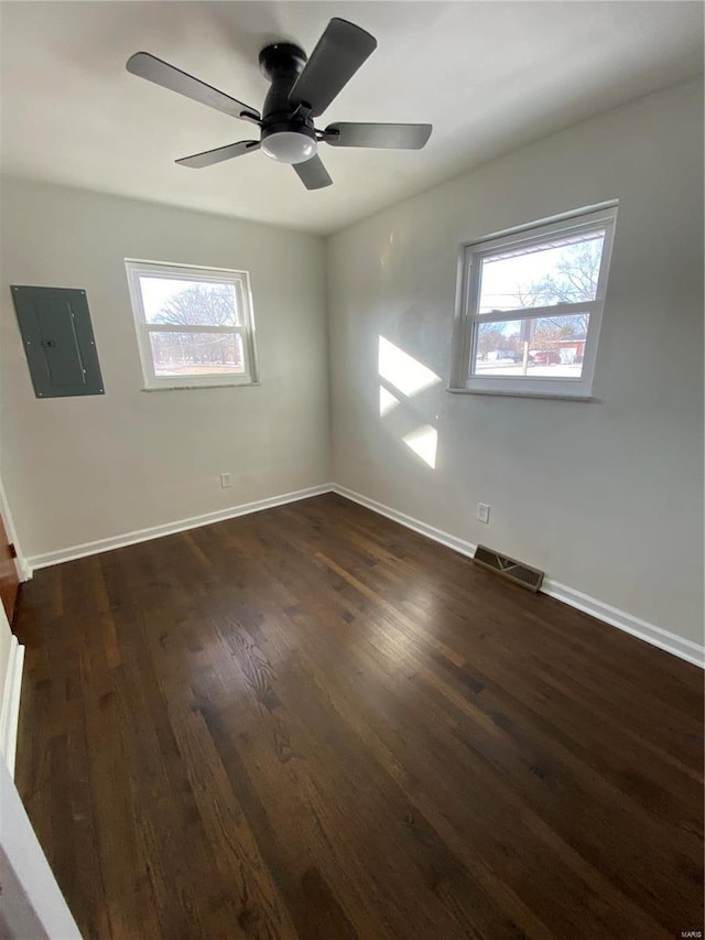 empty room with dark wood-type flooring, a wealth of natural light, and electric panel