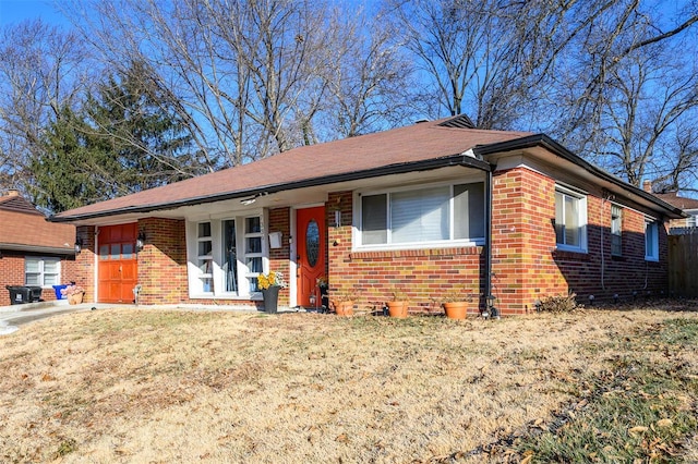 ranch-style home featuring a garage, covered porch, and a front yard