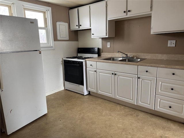 kitchen with white cabinetry, white fridge, sink, and gas range oven