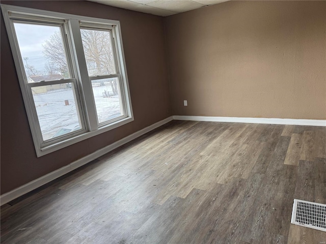 spare room with wood-type flooring and a drop ceiling