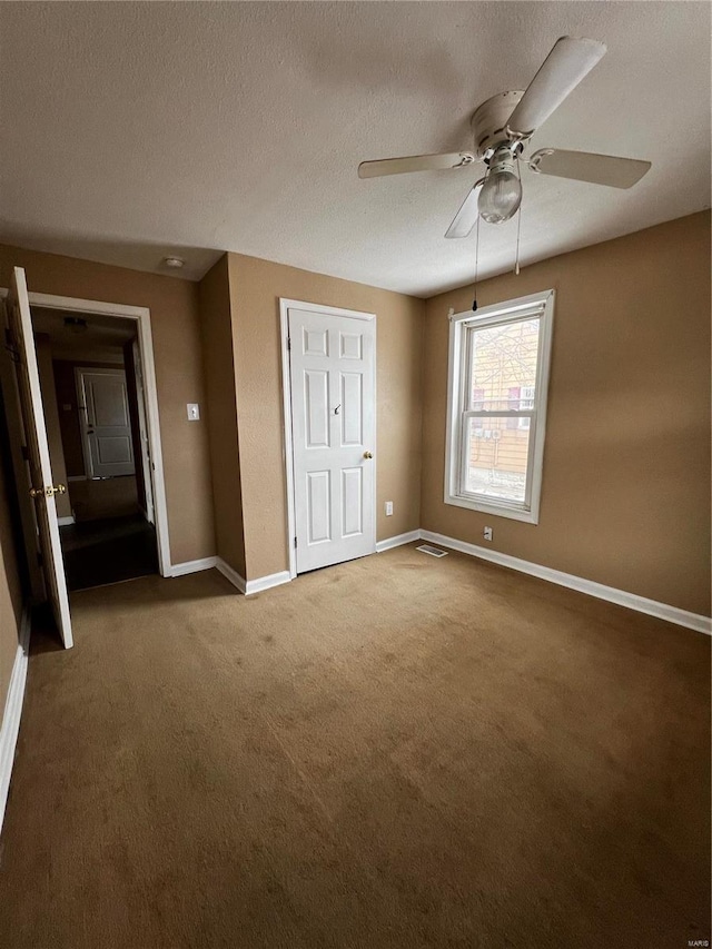 unfurnished bedroom featuring ceiling fan, carpet flooring, and a textured ceiling