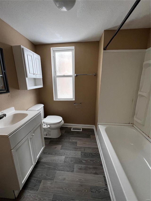 full bathroom with vanity, hardwood / wood-style flooring, a textured ceiling, and toilet