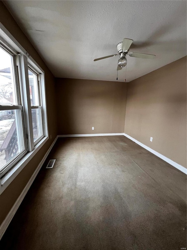 carpeted spare room with ceiling fan and a textured ceiling