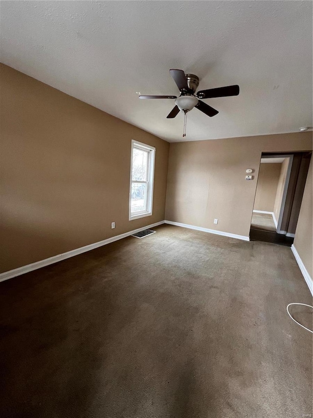 empty room featuring dark colored carpet and ceiling fan