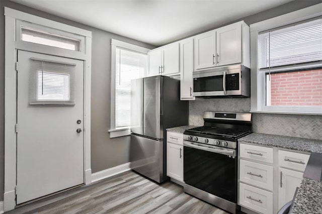 kitchen featuring white cabinetry, stainless steel appliances, light stone countertops, and tasteful backsplash