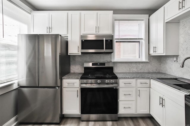 kitchen featuring sink, white cabinetry, dark stone countertops, appliances with stainless steel finishes, and decorative backsplash