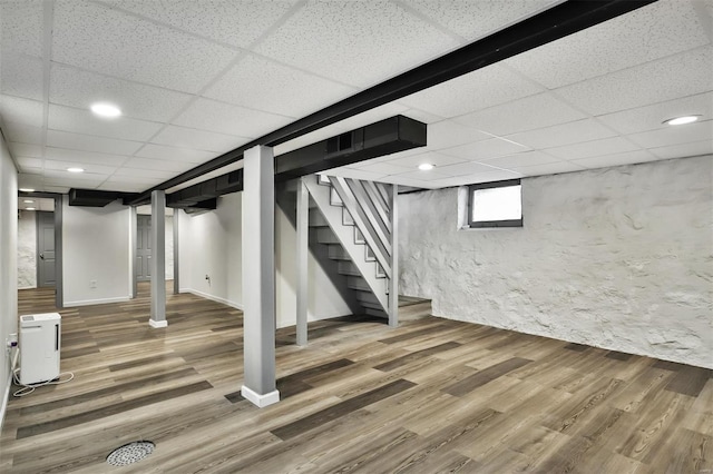 basement featuring a paneled ceiling and hardwood / wood-style floors