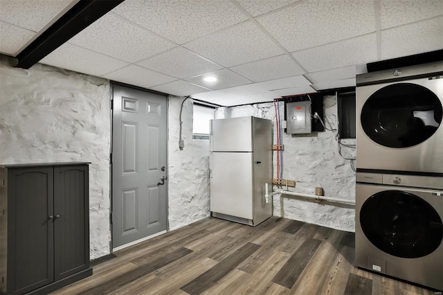 washroom with dark hardwood / wood-style floors, electric panel, and stacked washer and clothes dryer