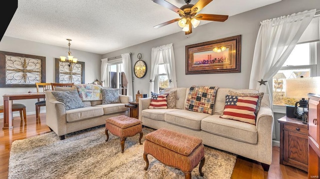 living room with ceiling fan with notable chandelier, a textured ceiling, and light hardwood / wood-style floors