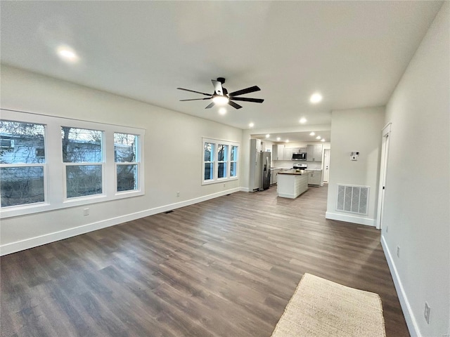 unfurnished living room featuring ceiling fan and dark hardwood / wood-style floors