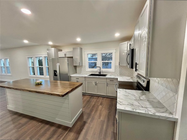 kitchen with sink, stainless steel appliances, dark hardwood / wood-style floors, a center island, and tasteful backsplash