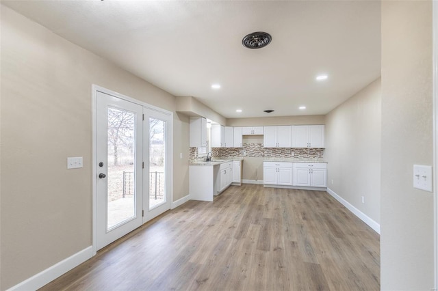 kitchen with sink, white cabinets, light hardwood / wood-style floors, and decorative backsplash