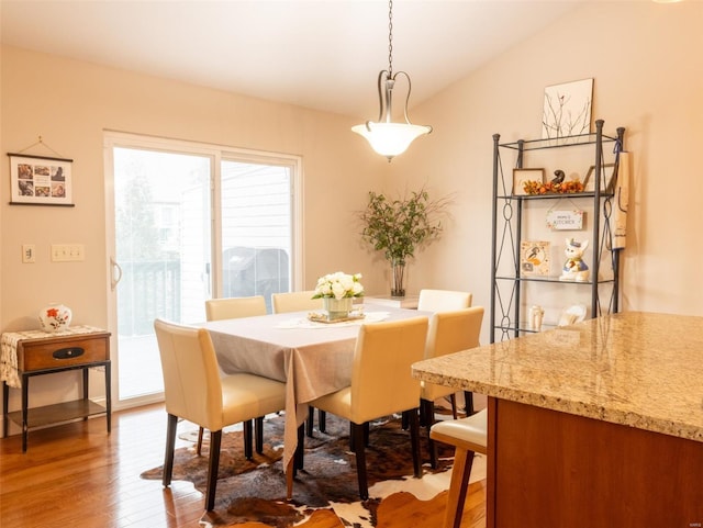 dining area featuring vaulted ceiling and wood-type flooring