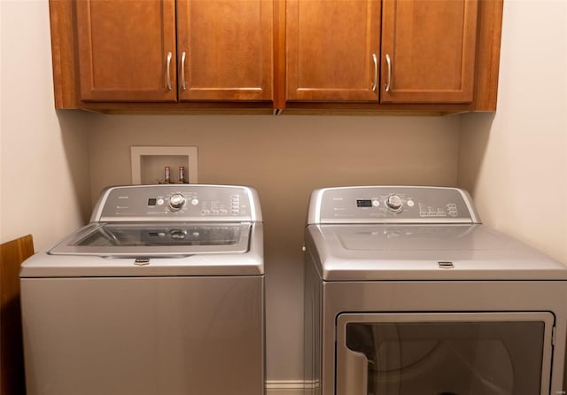 clothes washing area with cabinets and washing machine and clothes dryer