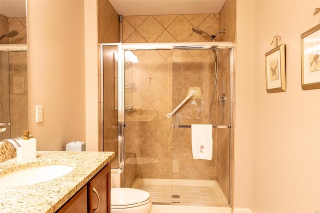 bathroom with vanity, a shower with door, and toilet