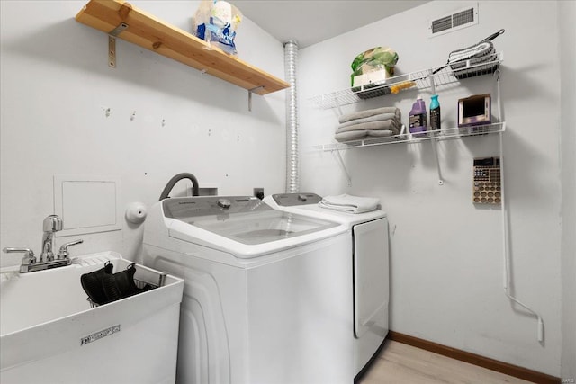 laundry room featuring sink, washing machine and clothes dryer, and light wood-type flooring