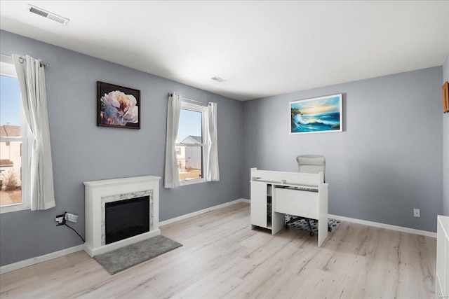 office space featuring a high end fireplace and light wood-type flooring